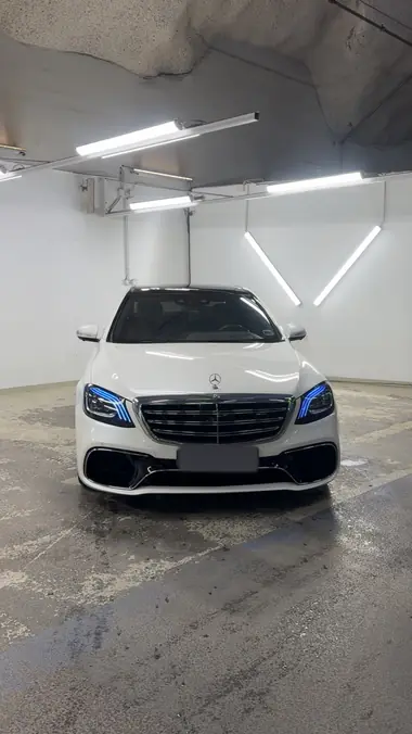 Valkoinen Mercedes-AMG S 63 edestä hallin valaistuksessa